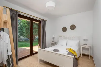 a bedroom with a white bed and a sliding glass door at 3 Roses Residence in Afantou