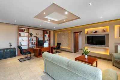 a living room with a couch and a desk and a tv at 3 Roses Residence in Afantou