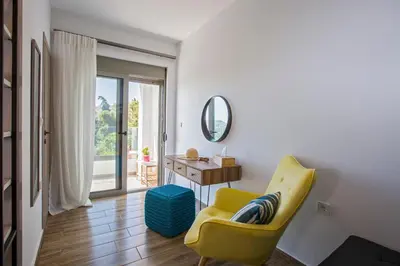 a living room with a yellow chair and a mirror at My Home in RHO in Koskinou
