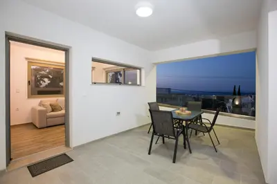 a dining room and living room with a table and chairs at My Home in RHO in Koskinou