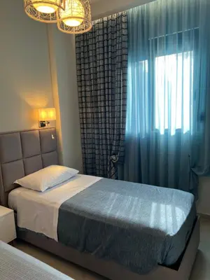 a bedroom with a bed and a window with blue curtains at Psaropoula's Hidden Gem in Rhodes Town