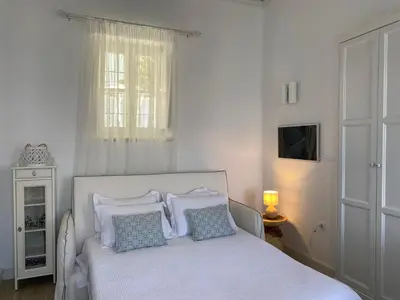 a bedroom with a white bed with pillows and a window at Halki Sea Breeze - a waterfront villa in Halki