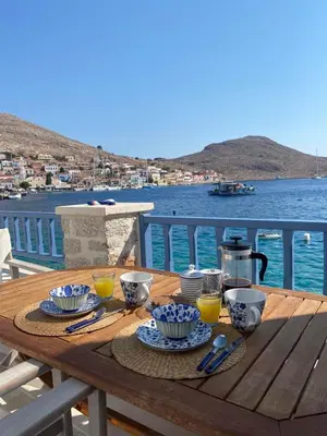 a wooden table with food and drinks on top of the water at Halki Sea Breeze - a waterfront villa in Halki