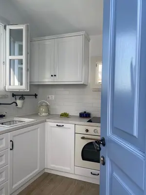 a kitchen with white cabinets and a blue door at Halki Sea Breeze - a waterfront villa in Halki