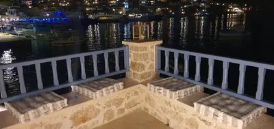 a balcony with a view of the water at night at Halki Sea Breeze - a waterfront villa in Halki
