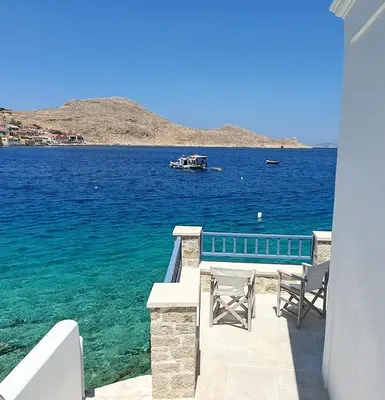 a balcony with a view of the water and a boat at Halki Sea Breeze - a waterfront villa in Halki