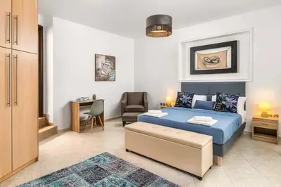 a bedroom with a blue bed and a chair at Villa Ifigeneia in Afantou