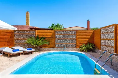 a swimming pool in front of a wooden fence at Villa Ifigeneia in Afantou