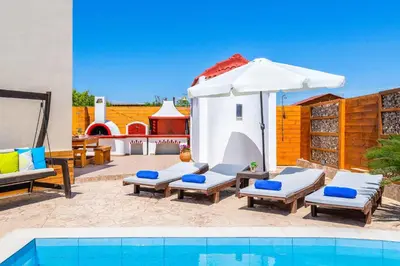 a patio with a swimming pool and an umbrella and chairs at Villa Ifigeneia in Afantou
