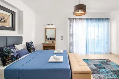 a bedroom with a blue bed and a couch at Villa Ifigeneia in Afantou