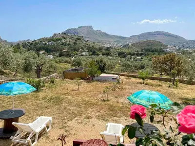 two chairs and umbrellas on a field with mountains at Rhodes traditional Cottage with private garden in Archangelos