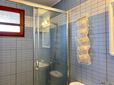 a blue tiled bathroom with a shower and a toilet at Rhodes traditional Cottage with private garden in Archangelos