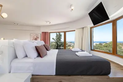 a bedroom with a large bed with large windows at Hamilton Grand Villa in Koskinou
