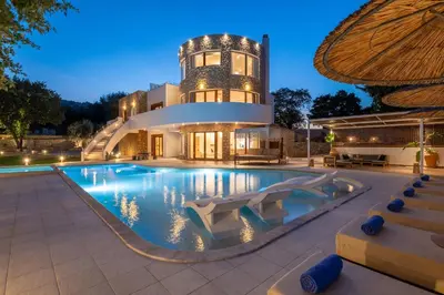 a house with a swimming pool in front of a building at Hamilton Grand Villa in Koskinou