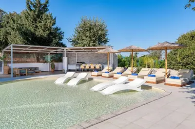 a swimming pool with lounge chairs and umbrellas at Hamilton Grand Villa in Koskinou