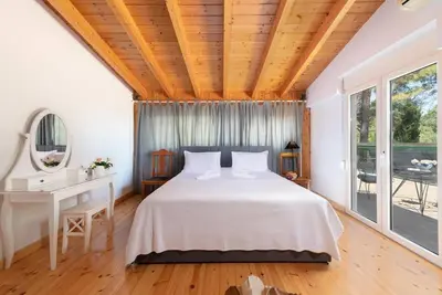 a bedroom with a bed and a desk and windows at AGROLUX OASIS - A Private Pool Escape in Lush Agricultural Serenity in Sálakos