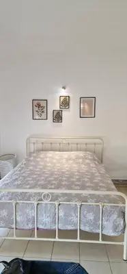 a white bed in a room with pictures on the wall at Cosy little studio for family vacations ! in Rhodes Town