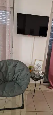 a living room with a green chair and a tv at Cosy little studio for family vacations ! in Rhodes Town