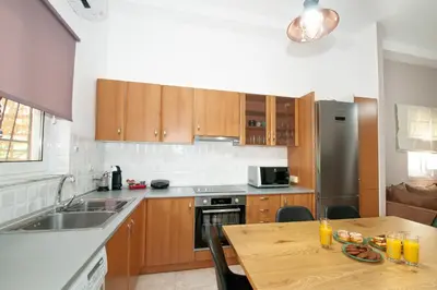 a kitchen with wooden cabinets and a wooden table at Vicinia Guest House in Rhodes Town