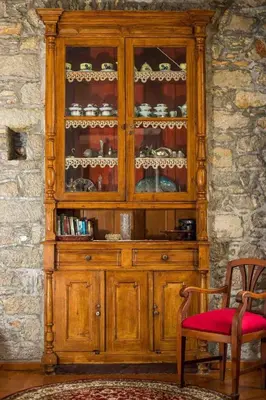 a wooden hutch with dishes in it next to a chair at Myrsini's House in Symi