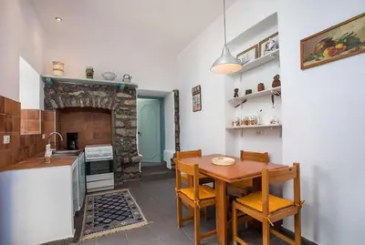 a kitchen with a wooden table and a fireplace at Myrsini's House in Symi