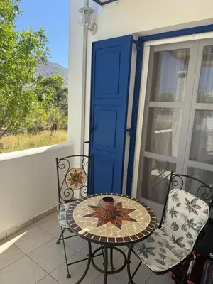 a table and chairs on a balcony with a blue door at Deda Apartments in Livadia