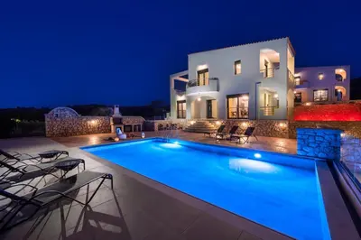 a villa with a swimming pool at night at Alki Slow Living Villas in Afantou