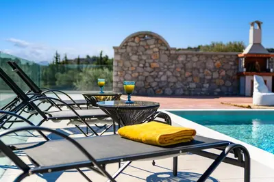 a patio table with two glasses of wine on it at Alki Slow Living Villas in Afantou