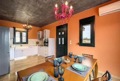 a kitchen and dining room with a wooden table and chairs at Alki Slow Living Villas in Afantou