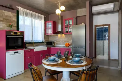 a kitchen with red cabinets and a table with chairs at Alki Slow Living Villas in Afantou
