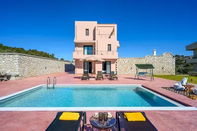 a villa with a swimming pool in front of a house at Alki Slow Living Villas in Afantou
