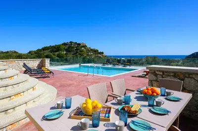 a table with fruit on it next to a swimming pool at Alki Slow Living Villas in Afantou