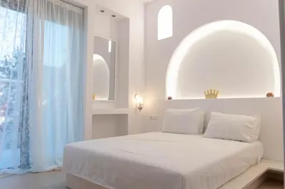 a white bedroom with a large bed and a window at Villa Iliousa Princess in Psinthos