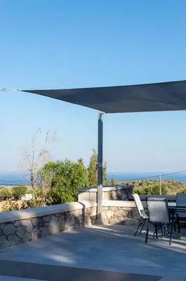 a patio with a table and chairs under a canopy at Villa Iliousa Princess in Psinthos