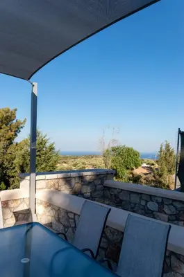 a patio with a table and chairs on a stone wall at Villa Iliousa Princess in Psinthos