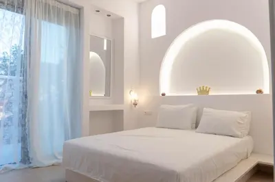 a white bedroom with a large bed and a window at Villa Iliousa Princess in Psinthos