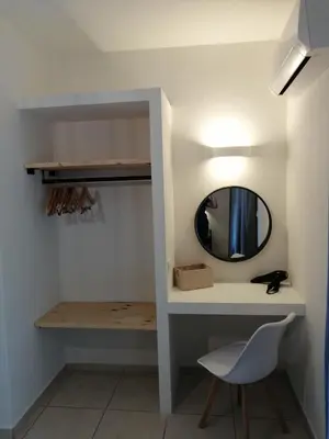 a bathroom with a mirror and a chair in a room at OASIS APARTMENTS in Livadia