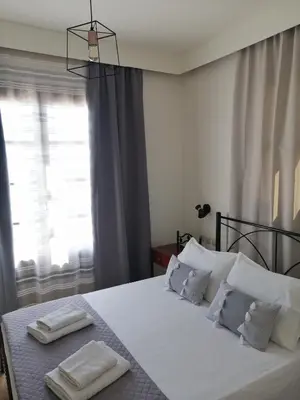a bedroom with a bed with white sheets and pillows at OASIS APARTMENTS in Livadia