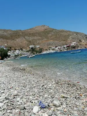 a rocky beach with boats on the water at OASIS APARTMENTS in Livadia