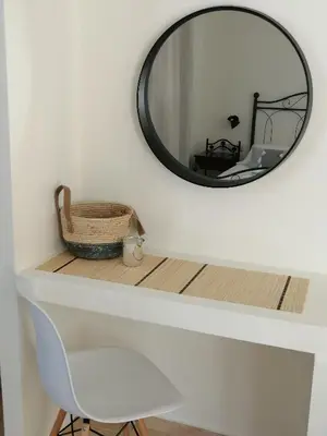 a mirror on a wall next to a white chair at OASIS APARTMENTS in Livadia