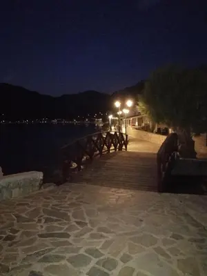 a wooden boardwalk next to the water at night at OASIS APARTMENTS in Livadia