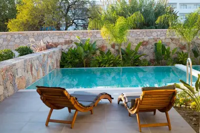 a patio with two chairs and a swimming pool at DeLight Luxury Rooms in Faliraki