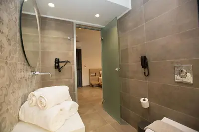 a bathroom with a shower with towels on a bench at DeLight Luxury Rooms in Faliraki