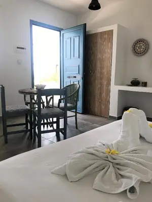 a bedroom with a white bed with a table and chairs at Anastasia's Garden in Archangelos
