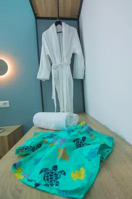 a bedroom with a bed with a white robe on a rack at Ialemos Group in Symi