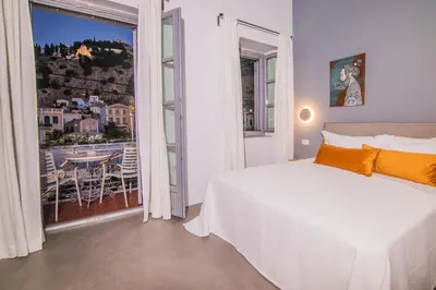 a bedroom with a bed and a balcony with a table at Ialemos Group in Symi