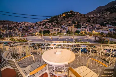 a balcony with a table and chairs and a city at Ialemos Group in Symi