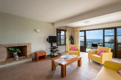 a living room with yellow chairs and a fireplace at Aegean Blue Villa's - All Inclusive & Water park in Kalathos