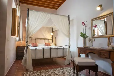 a bedroom with a canopy bed with a table and a piano at Villa Amalia in Líndos
