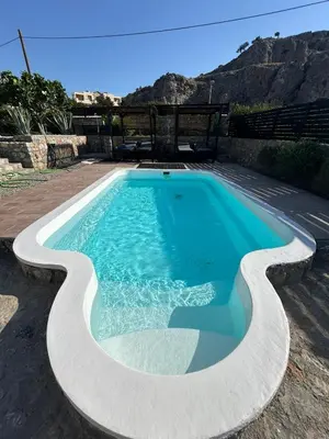 a swimming pool with blue water and mountains in the background at Villa Poseidon Blue in Rhodes Town